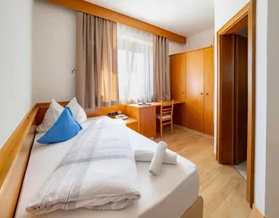 a bedroom with a large bed and a desk at Hotel Weinberg in Appiano sulla Strada del Vino