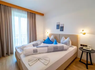 a bedroom with a large bed with blue pillows at Hotel Weinberg in Appiano sulla Strada del Vino