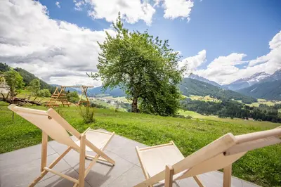 two chairs sitting on a patio with a view of mountains at Agriturismo MARER Urlaub auf dem Bauernhof in Villabassa