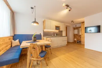 a kitchen with a wooden table and a blue couch at Agriturismo MARER Urlaub auf dem Bauernhof in Villabassa