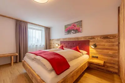 a bedroom with a large bed with a wooden headboard at Agriturismo MARER Urlaub auf dem Bauernhof in Villabassa