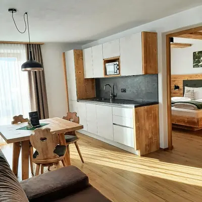 a kitchen and dining room with a table and a bed at Agriturismo MARER Urlaub auf dem Bauernhof in Villabassa
