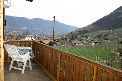 a white chair sitting on a balcony with a view of a town at Garni & Residence Sonngart in Lagundo