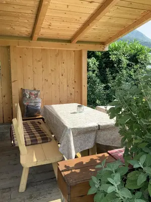 a table and chair on a patio with a wooden roof at Garni & Residence Sonngart in Lagundo