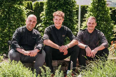 three men sitting on a bench in a garden at Hotel Sun in Naz-Sciaves