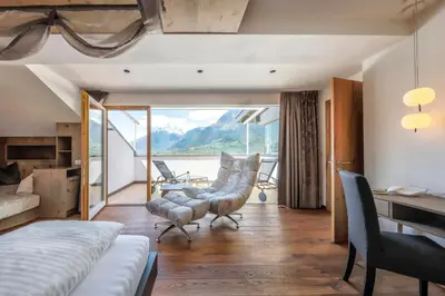 a bedroom with a bed and a desk and chairs at Hotel Schlosswirt in Schenna
