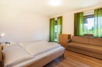 a bedroom with a bed and a window with green curtains at Obstbauernhof Bundschuh - Dogs welcome in Appiano sulla Strada del Vino