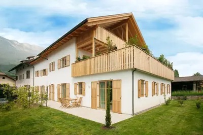 a large white house with a wooden roof at Obstbauernhof Bundschuh - Dogs welcome in Appiano sulla Strada del Vino