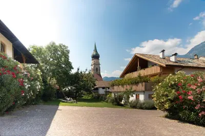 a building with a church with a clock tower at Obstbauernhof Bundschuh - Dogs welcome in Appiano sulla Strada del Vino