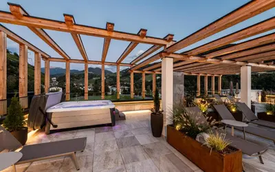 a pergola with a bed and chairs on a patio at Hotel Klostersepp in Chiusa