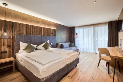 a bedroom with a large bed with a wooden wall at Hotel Klostersepp in Chiusa