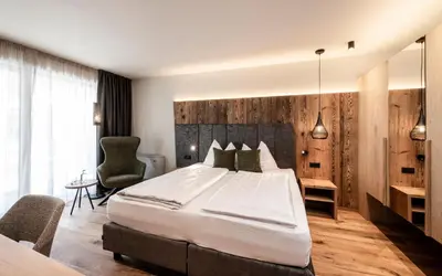 a bedroom with a large bed and a desk at Hotel Klostersepp in Chiusa