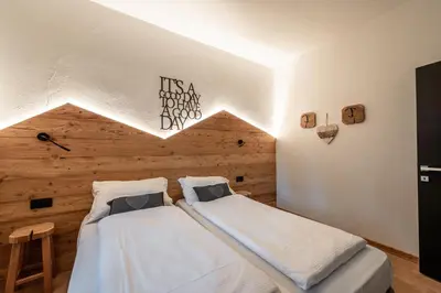 two beds in a room with a wooden wall at -Antermoia- Appartament Canazei Center in Canazei