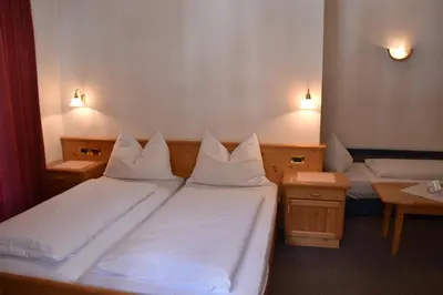 a bedroom with two beds with white sheets and lights at Garni Haus Tyrol in Corvara in Badia