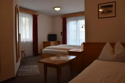 a hotel room with two beds and a table at Garni Haus Tyrol in Corvara in Badia