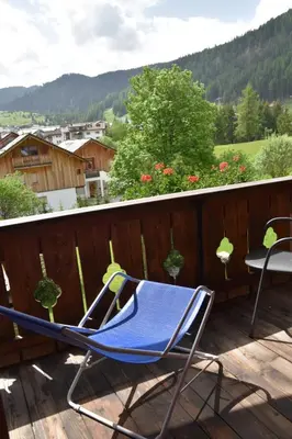 a blue lawn chair sitting on a deck with a table at Garni Haus Tyrol in Corvara in Badia