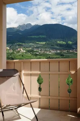 a chair on a balcony with a view of a mountain at Pension Schweigkofler in Tirolo