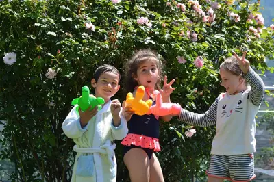 three children playing with toys in front of a tree at Pension Schweigkofler in Tirolo