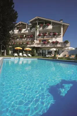 a large swimming pool in front of a building at Pension Schweigkofler in Tirolo