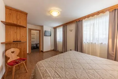 a bedroom with a bed and a chair and a window at Residence Adler in San Martino di Castrozza