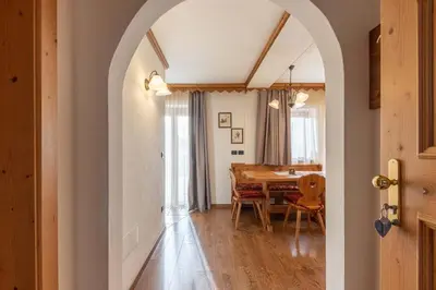 an archway leads into a dining room with a table at Residence Adler in San Martino di Castrozza