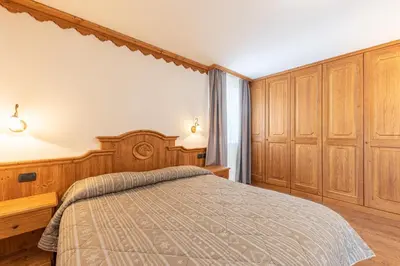 a bedroom with a bed and wooden cabinets at Residence Adler in San Martino di Castrozza