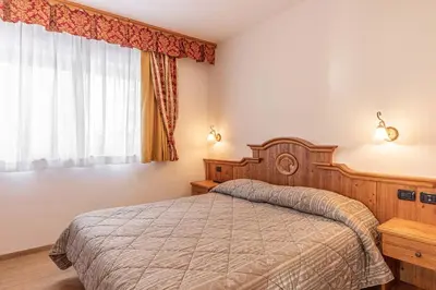 a bedroom with a bed and a window at Residence Adler in San Martino di Castrozza
