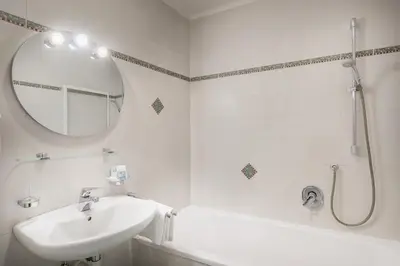 a white bathroom with a sink and a mirror at Gasthof Traube in San Lorenzo di Sebato