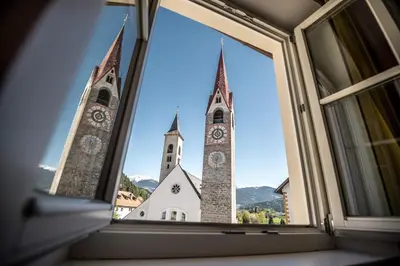 a church with two towers viewed through a window at Gasthof Traube in San Lorenzo di Sebato