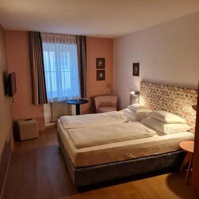 a hotel room with a large bed and a chair at Gasthof Traube in San Lorenzo di Sebato