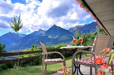 a patio with a table and chairs and mountains at Hotel Klarnerhof in Schenna