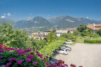 a group of cars parked in a parking lot with mountains at Hotel Klarnerhof in Schenna