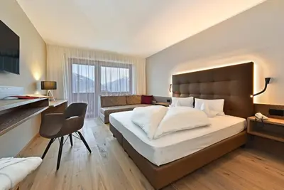 a bedroom with a large bed and a couch at Hotel Klarnerhof in Schenna