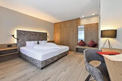 a bedroom with a bed and a desk and a table at Hotel Klarnerhof in Schenna