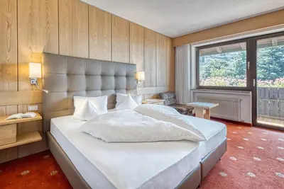 a bedroom with a large bed and a large window at Hotel Klarnerhof in Schenna