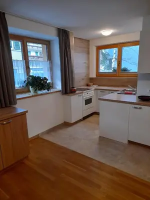 an empty kitchen with white cabinets and windows at Apartments Annemarie in Ortisei