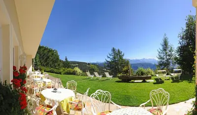 a group of tables and chairs on a lawn at Hotel König Laurin in San Genesio Atesino