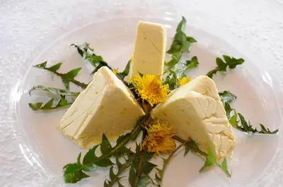 a plate with two slices of cheese and flowers on it at Hotel König Laurin in San Genesio Atesino