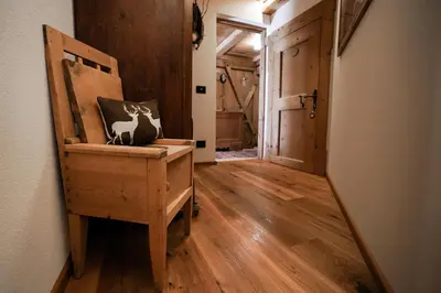 a hallway with a wooden chair with a cow on it at Lüch de Martin in La Valle