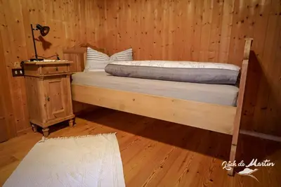 a bed in a wooden room with a wooden floor at Lüch de Martin in La Valle