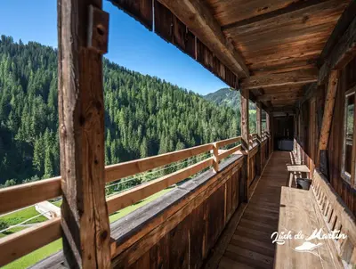 a balcony of a log cabin with a view of the mountains at Lüch de Martin in La Valle