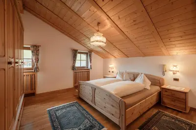 a bedroom with a bed and a wooden ceiling at Luech da Plazola in Selva di Val Gardena