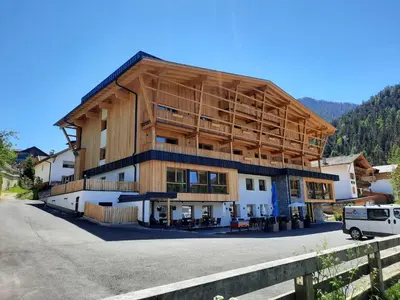 a large wooden building with a van parked in front at Hotel Gran Pre in San Vigilio Di Marebbe