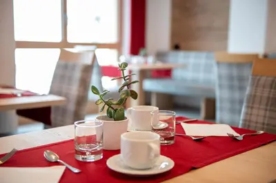 a table with a red napkin and glasses on it at Hotel Gran Pre in San Vigilio Di Marebbe