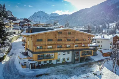 a building in the snow with mountains in the background at Hotel Gran Pre in San Vigilio Di Marebbe