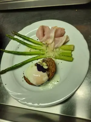 a plate of food with asparagus and a flower on it at Hotel Gran Pre in San Vigilio Di Marebbe