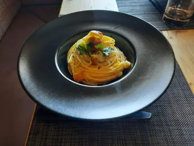 a bowl of pasta on a black plate on a table at Hotel Gran Pre in San Vigilio Di Marebbe