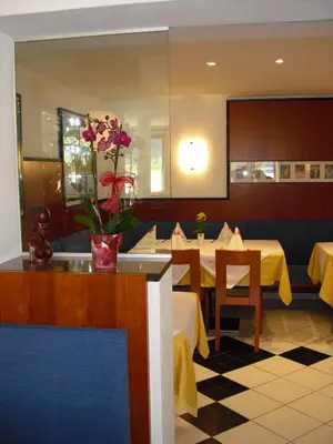 a restaurant with two tables and a vase of flowers at Pizzeria Restaurant Wieser in Rasùn di Sotto