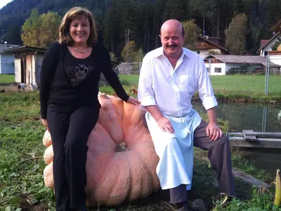 a man and a woman standing next to a large pumpkin at Pizzeria Restaurant Wieser in Rasùn di Sotto