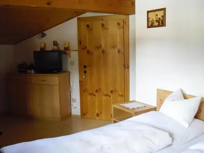 a bedroom with a bed and a wooden door at Pizzeria Restaurant Wieser in Rasùn di Sotto